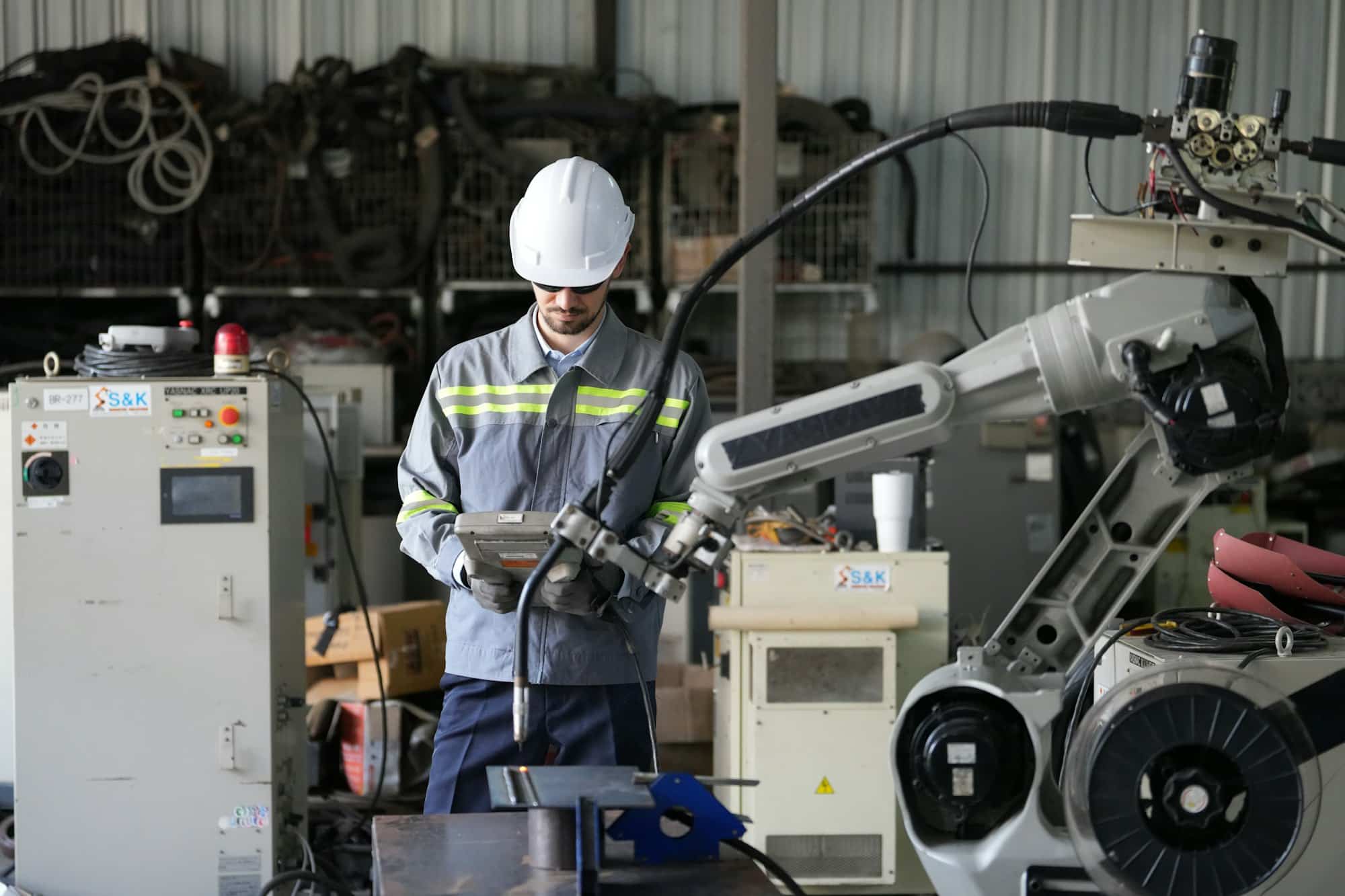 Robotics engineer working on maintenance of robotic arm in factory warehouse. Business technology.